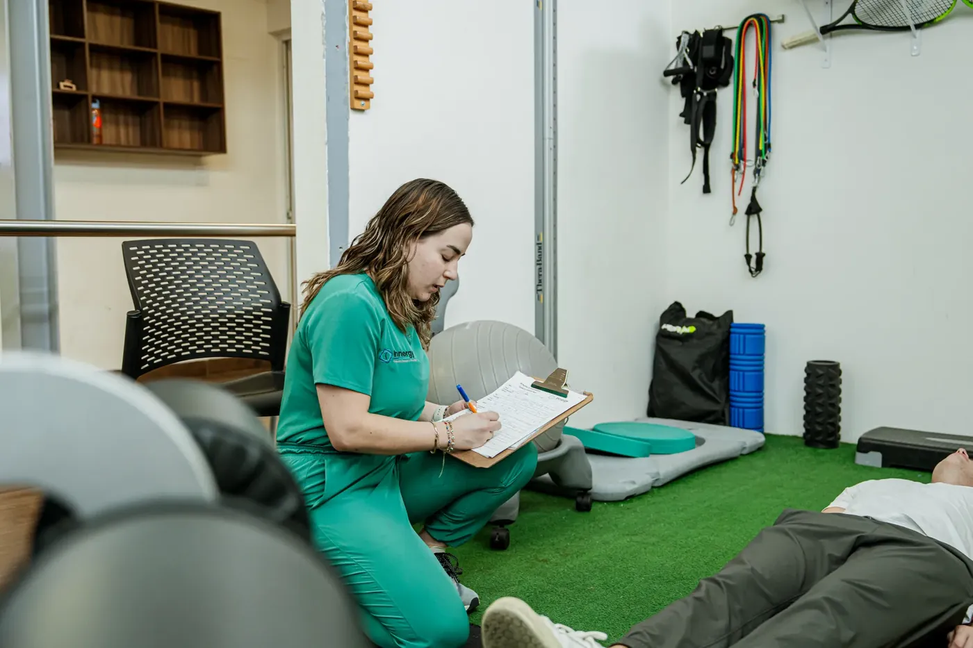 Fisioterapeuta tomando notas junto al paciente durante la sesión